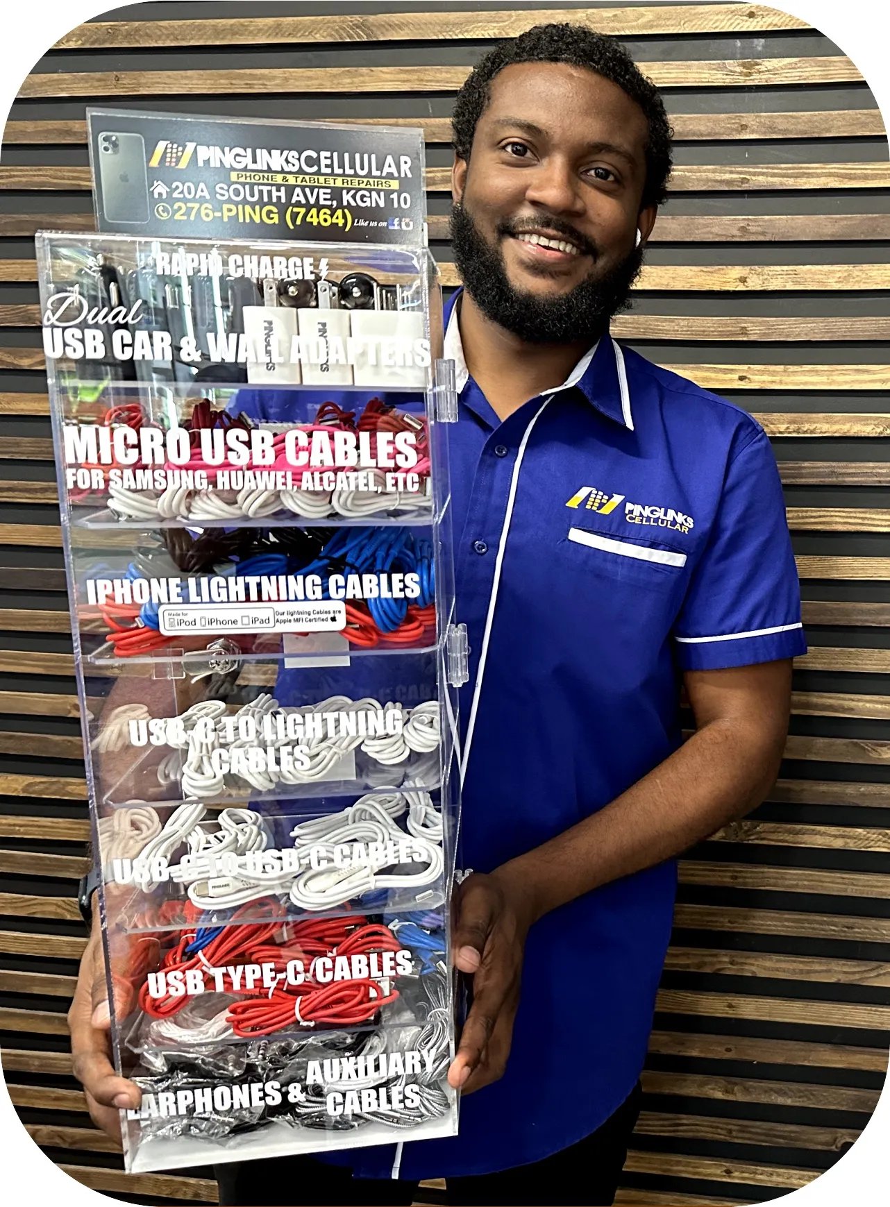 Pinglinks team member holding a Pinglinks Cellular counter-top display (20A South Ave, KGN 10, 276-PING) stocked with dual USB car and wall adapters, Micro USB, iPhone Lightning, USB-C to Lightning, USB-C to USB-C and USB Type-C cables, earphones and auxiliary cables